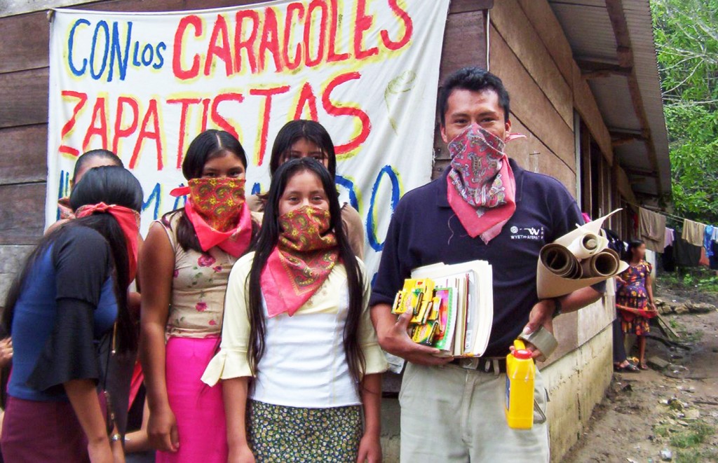 Zapatista teacher and students in front of a school building.