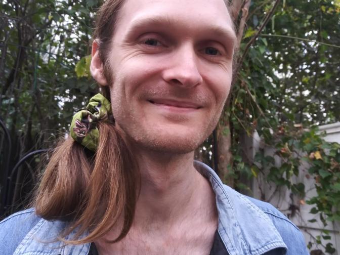 Keegan smiling, backgrounded by autumn lilacs