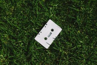 A white cassette tape laying in the grass.