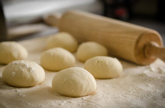 Seven fresh dough balls and a rolling pin.