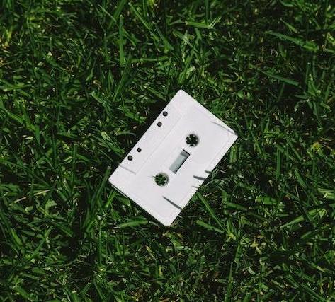 A white cassette tape laying in the grass.